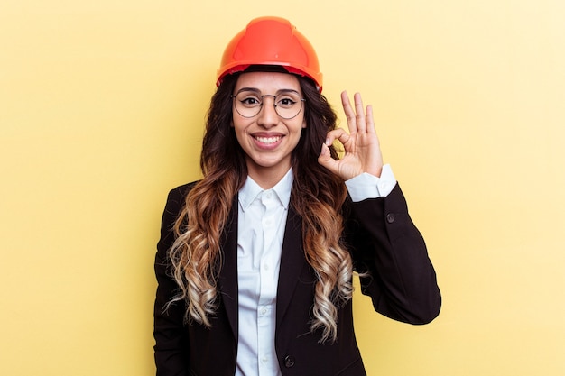 Young architect mixed race woman isolated on yellow background cheerful and confident showing ok gesture.