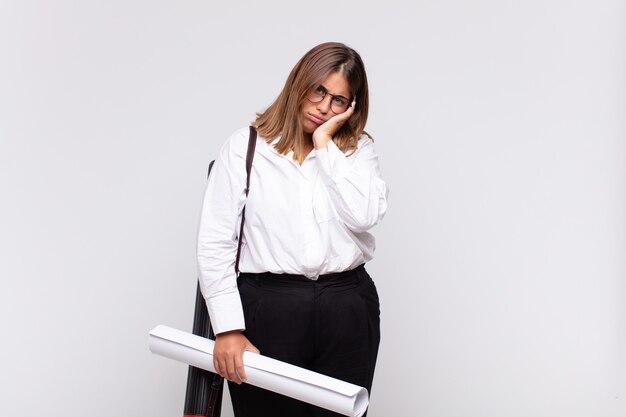 Young architect woman feeling bored, frustrated and sleepy after a tiresome, dull and tedious task, holding face with hand