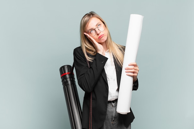 Young architect woman feeling bored, frustrated and sleepy after a tiresome, dull and tedious task, holding face with hand