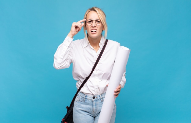 Young architect woman feeling confused and puzzled, showing you are insane, crazy or out of your mind