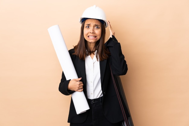 Young architect woman holding blueprints doing nervous gesture
