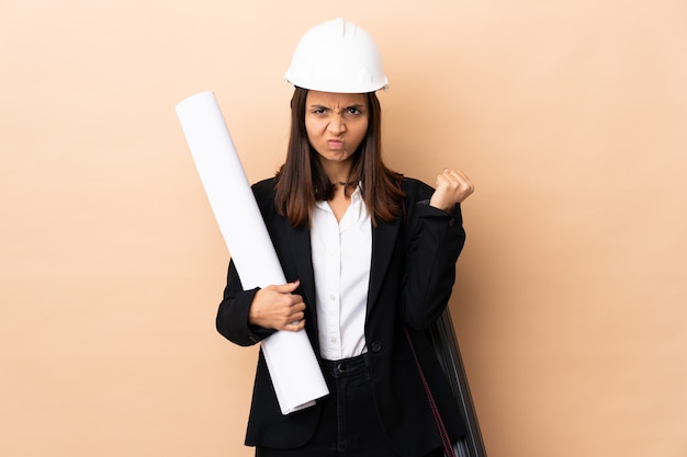 Young architect woman holding blueprints over isolated with unhappy expression