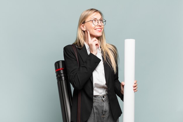 Young architect woman smiling happily and daydreaming or doubting, looking to the side