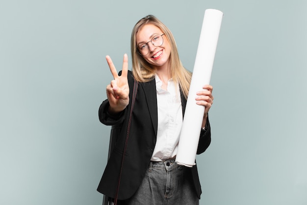 Giovane donna architetto sorridente e dall'aspetto amichevole, mostrando il numero due o il secondo con la mano in avanti, conto alla rovescia