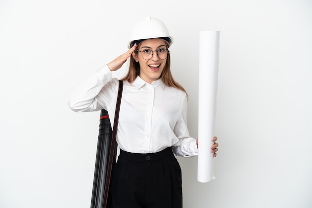 Young architect woman with helmet and holding blueprints on white with surprise expression