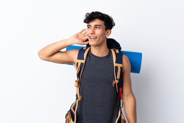 Young Argentinian hiker man over isolated white wall listening something