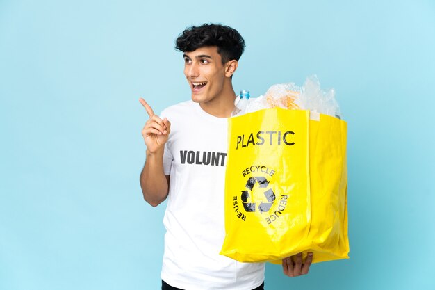 Young Argentinian man holding a bag full of plastic intending to realizes the solution while lifting a finger up