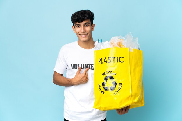 驚きの表情でプラスチックでいっぱいのバッグを持っている若いアルゼンチン人男性