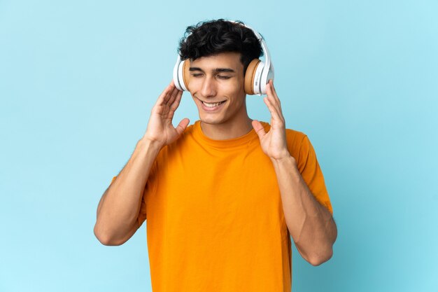 Young Argentinian man isolated on background listening music