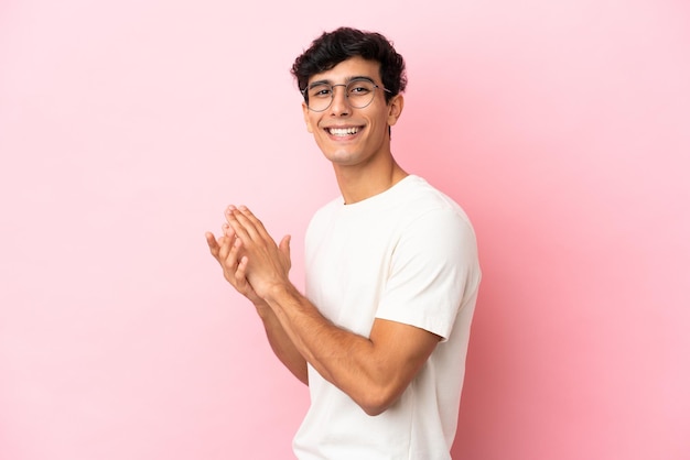 Young Argentinian man isolated on pink background applauding