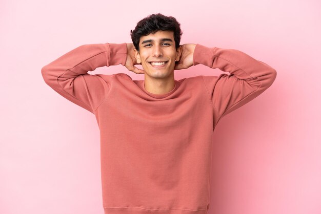 Young Argentinian man isolated on pink background laughing