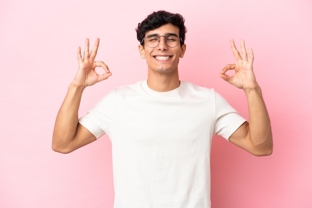 Young Argentinian man isolated on pink background in zen pose