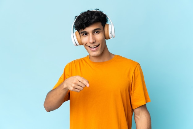 Young Argentinian man isolated on wall listening music