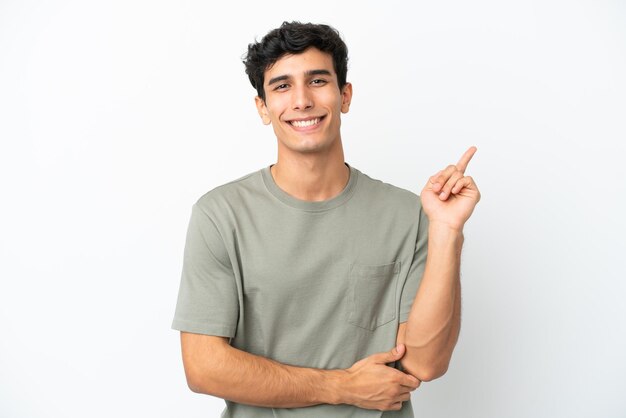 Young Argentinian man isolated on white background happy and pointing up