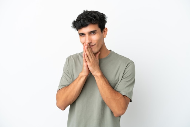 Young Argentinian man isolated on white background keeps palm together. Person asks for something