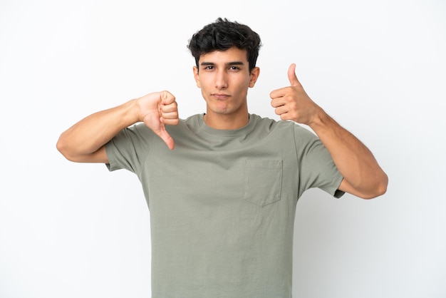 Young Argentinian man isolated on white background making goodbad sign Undecided between yes or not