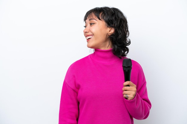 Young Argentinian singer woman isolated on white background laughing in lateral position