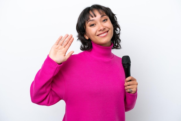 Young Argentinian singer woman isolated on white background saluting with hand with happy expression