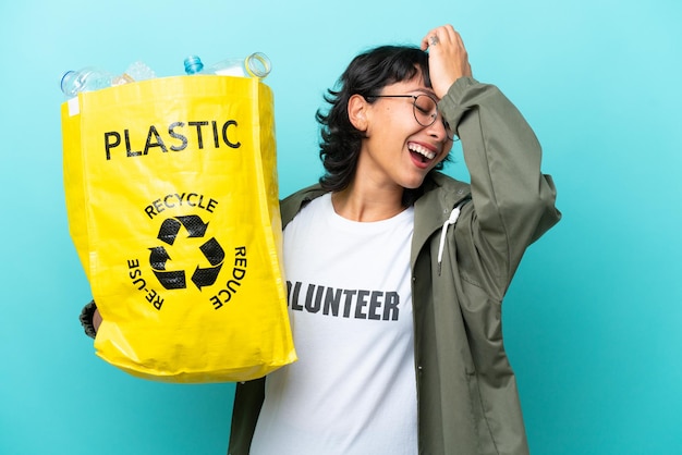 La giovane donna argentina con in mano una borsa piena di bottiglie di plastica da riciclare isolate su sfondo blu ha realizzato qualcosa e intende la soluzione