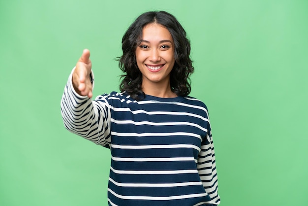 Young Argentinian woman over isolated background shaking hands for closing a good deal