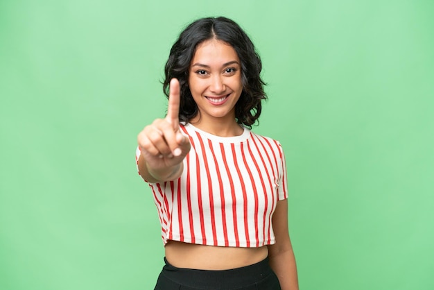 Young Argentinian woman over isolated background showing and lifting a finger