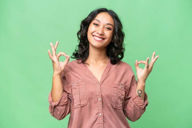 Foto giovane donna argentina sullo sfondo isolato che mostra il segno ok con due mani