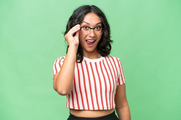 Young argentinian woman over isolated background with glasses and surprised