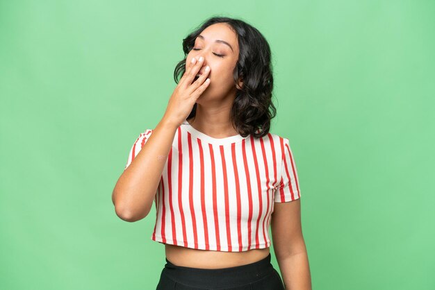 Young Argentinian woman over isolated background yawning and covering wide open mouth with hand