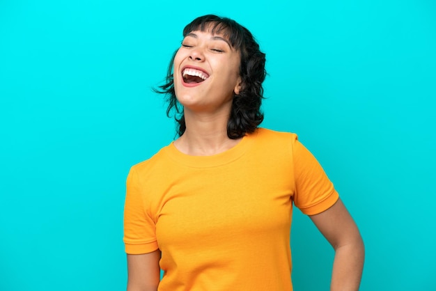 Young Argentinian woman isolated on blue background laughing