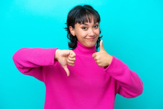 Photo young argentinian woman isolated on blue background making goodbad sign undecided between yes or not