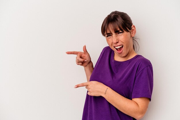 Young Argentinian woman isolated on white background pointing with forefingers to a copy space, expressing excitement and desire.