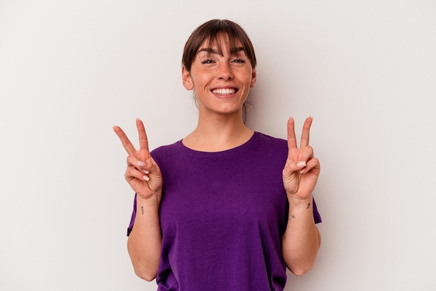 Young Argentinian woman isolated on white background showing victory sign and smiling broadly.