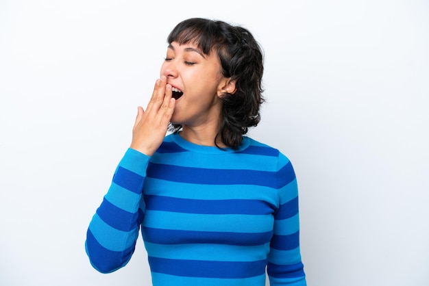 Young Argentinian woman isolated on white background yawning and covering wide open mouth with hand