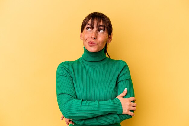 Young Argentinian woman isolated on yellow background dreaming of achieving goals and purposes