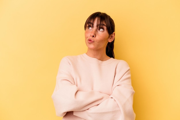 Young Argentinian woman isolated on yellow background dreaming of achieving goals and purposes