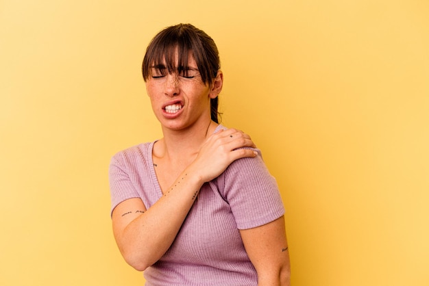 Young Argentinian woman isolated on yellow background having a shoulder pain.