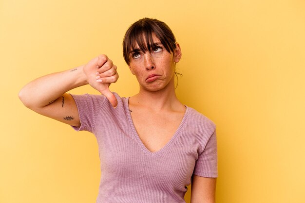 Young Argentinian woman isolated on yellow background showing a dislike gesture, thumbs down. Disagreement concept.