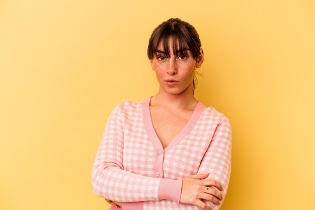 Young Argentinian woman isolated on yellow background suspicious, uncertain, examining you.