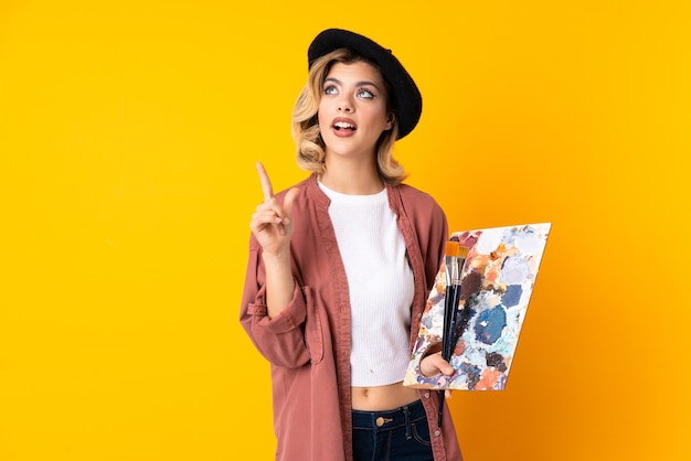 Young artist girl holding a palette with paint