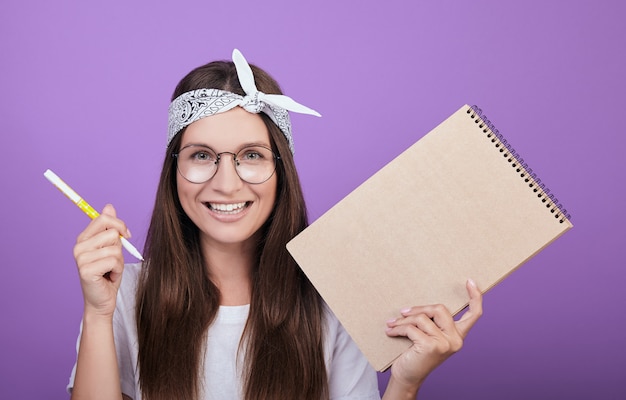 A young artist holds an album and a pen in her hands.