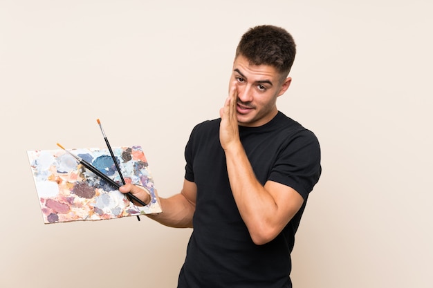 Молодой художник человек над изолированной стеной шепчет что-то