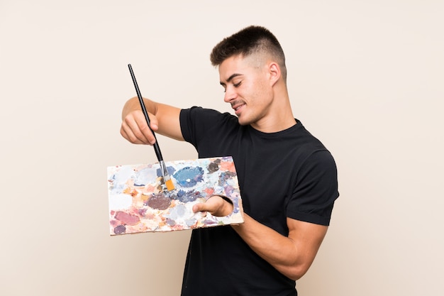 Young artist man over isolated wall