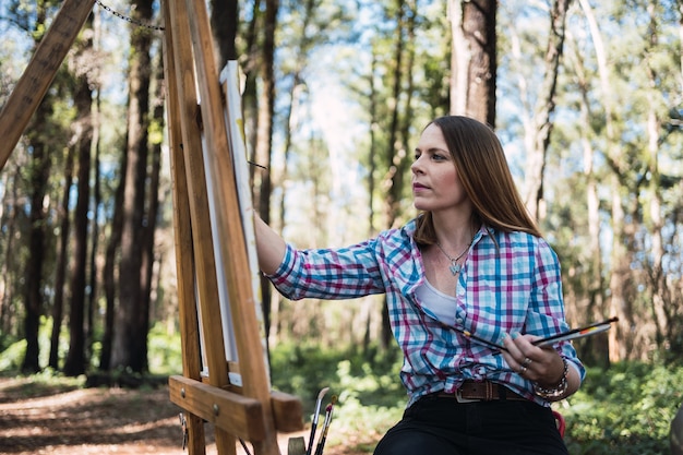 Young artist painting in the park in autumn.