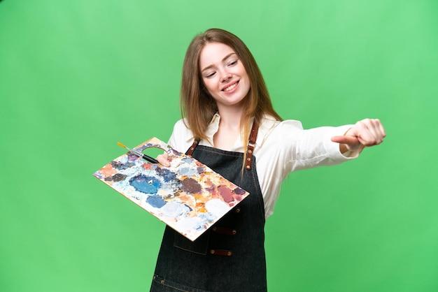 Young artist woman holding a palette over isolated chroma key background giving a thumbs up gesture