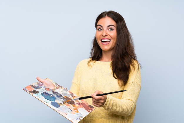 Young artist woman over isolated blue wall