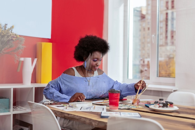 Photo young artist. young promising artist holding painting brush feeling inspired and joyful while working