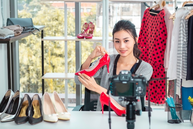 Young Asia friendly girl live video blog (vlogger) and sales shoes in online e-commerce shopping at shop.