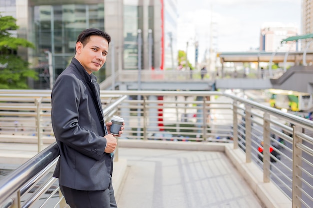 Young Asia handsome businessman drinking hot coffee in the modern city