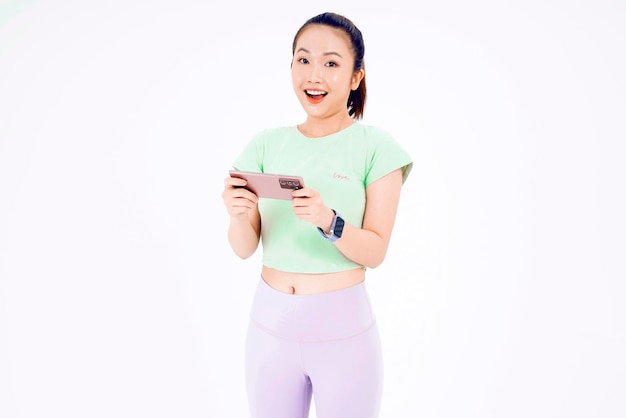 젊은 아시아 여성은 긍정적인 표정으로 빈 스마트 폰 화면을 보여주며 여성 손에 흰색 화면이 있는 파란색 배경 휴대 전화에서 캐주얼한 옷을 입고 활짝 웃고 있습니다.