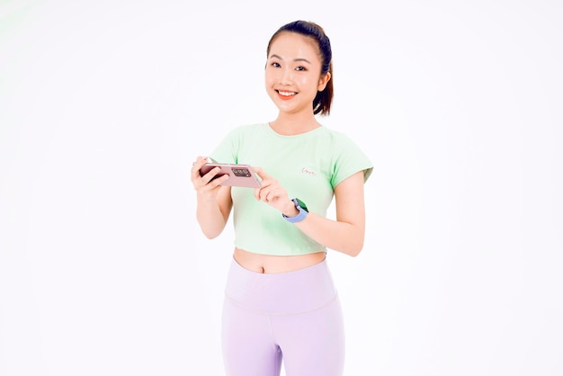 Young Asia lady show empty smart phone screen with positive expression smiles broadly dressed in casual clothing feeling happiness on blue background Mobile phone with white screen in female hand